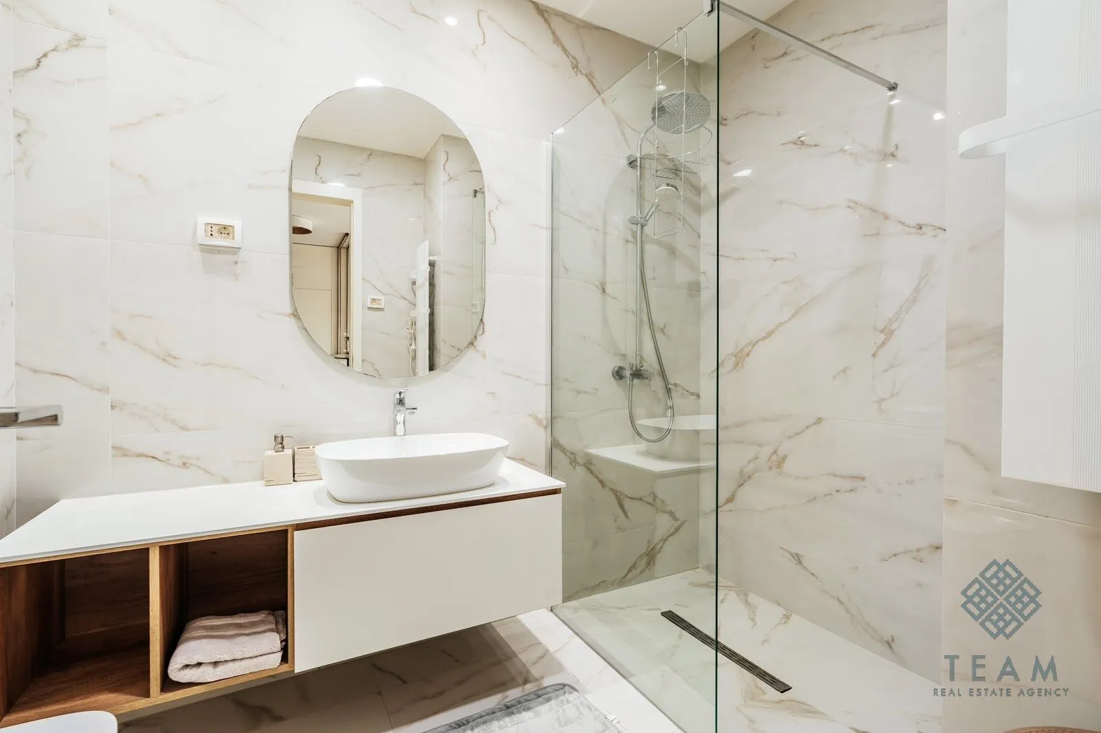 A modern bathroom equipped with a washbasin and a glass walk-in shower.