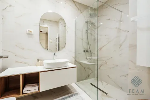 A modern bathroom equipped with a washbasin and a glass walk-in shower. - image 9