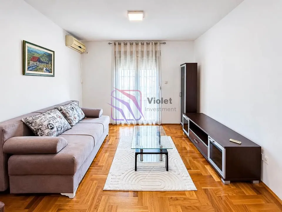 Living room with a sofa set, TV unit, and access to the terrace.