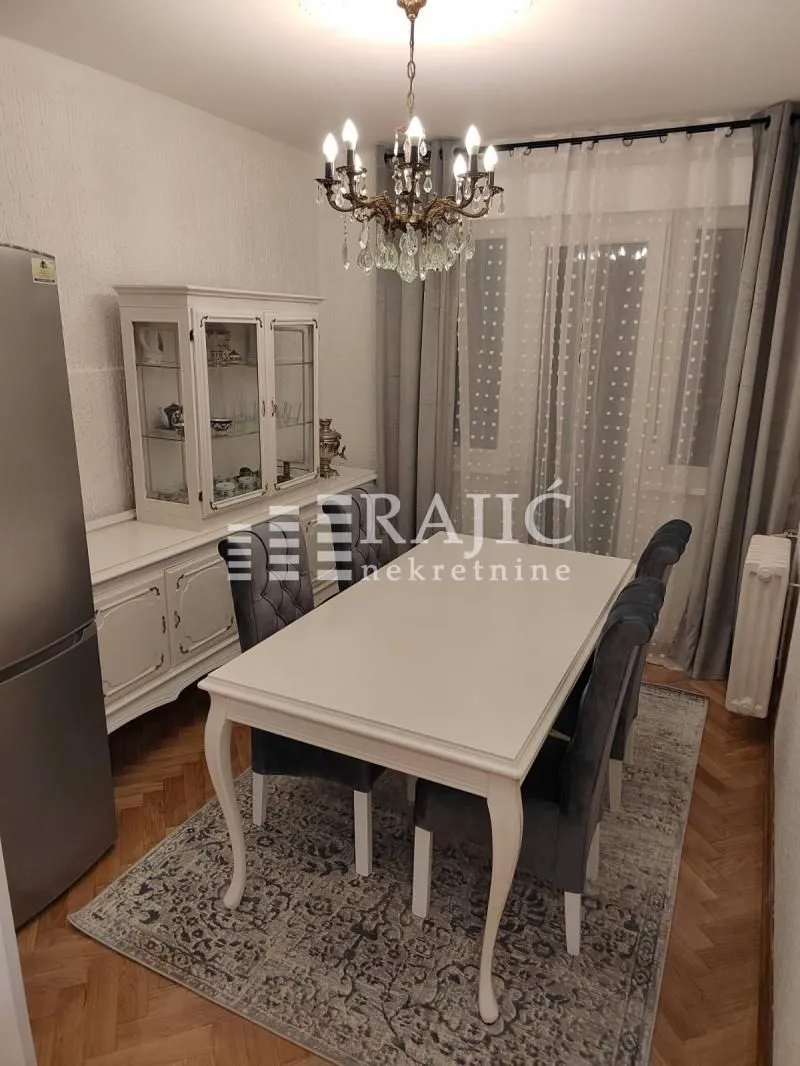 Dining room with a white table, chairs, and a display cabinet in an apartment.