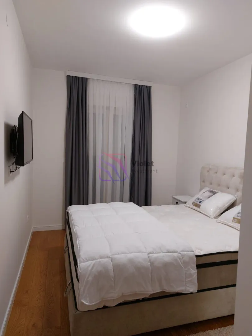 Bedroom with a double bed, a window, and a wall-mounted TV.