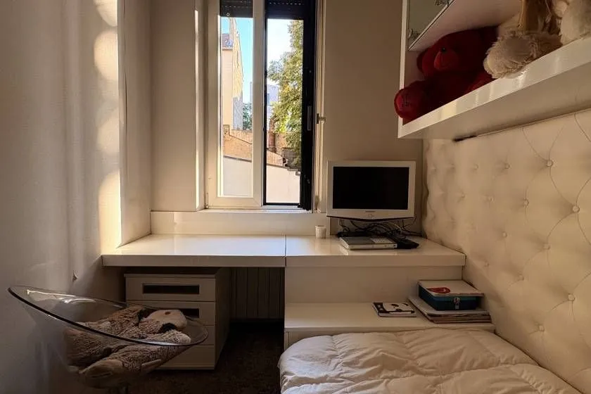 Small bedroom with a bed, desk, and window.