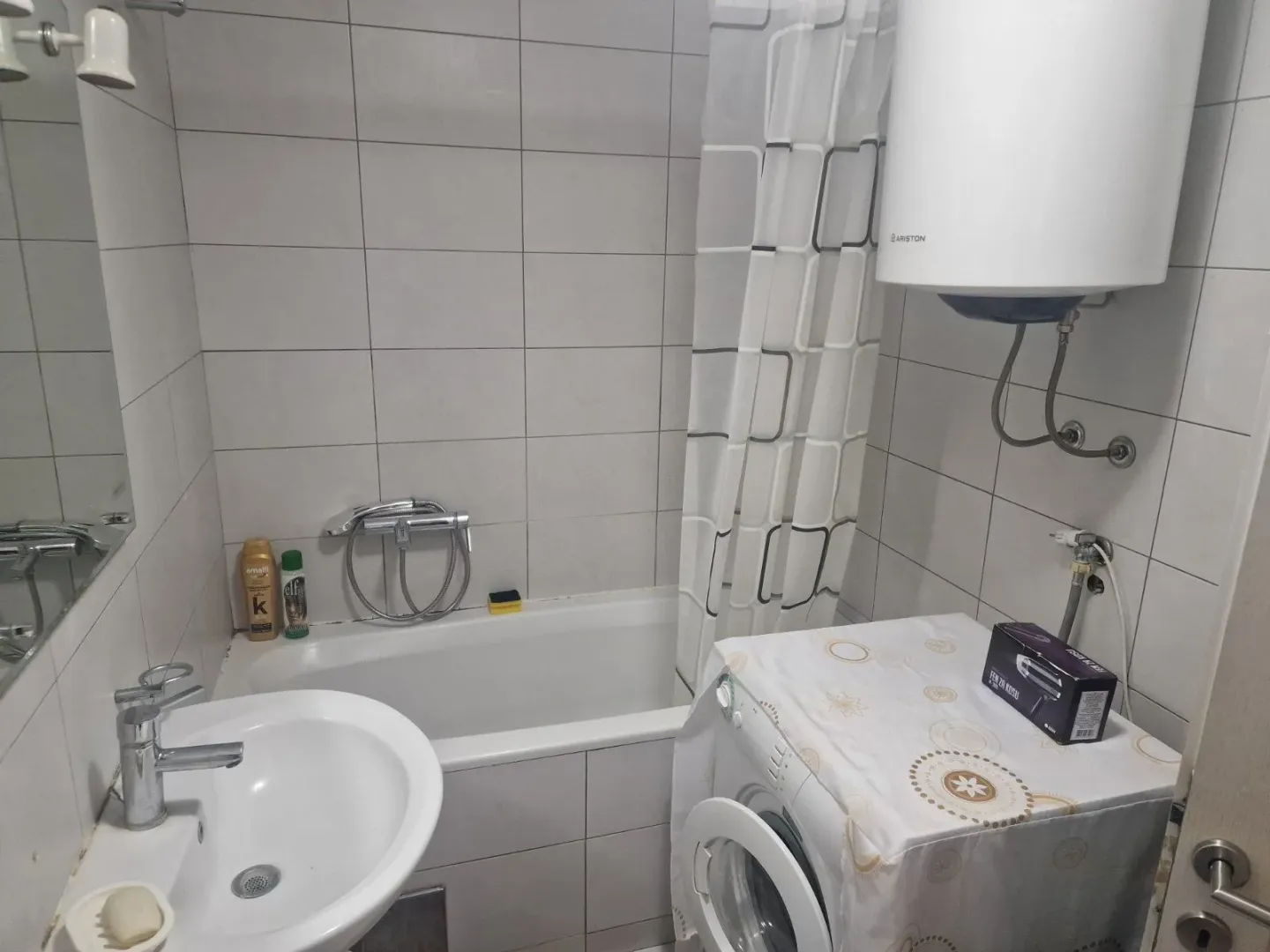 Manje kupatilo sa kadom, umivaonikom i veš mašinom.