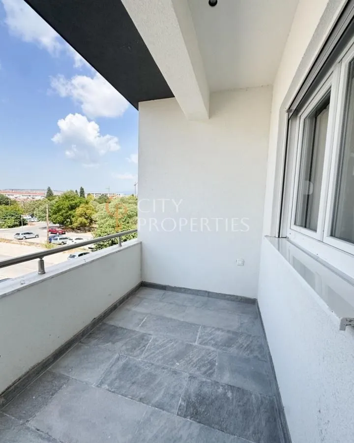 Natkriveni balkon sa popločanim podom i pogledom na okolinu.