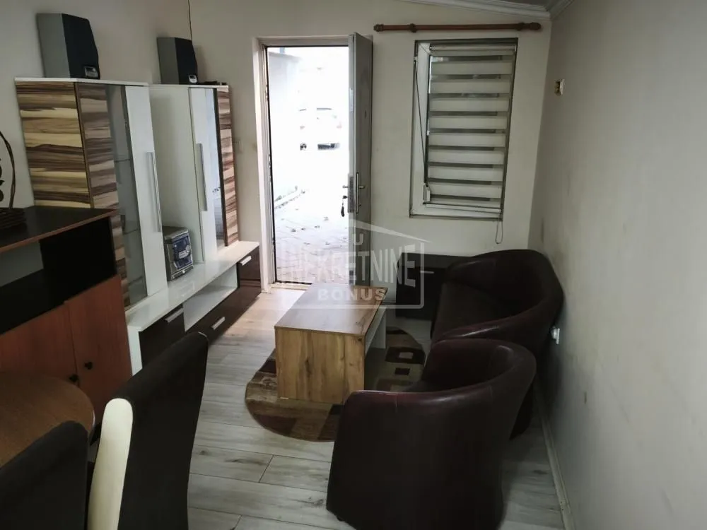 Manja dnevna soba sa garniturom za sedenje, klub stočićem i izlazom napolje.