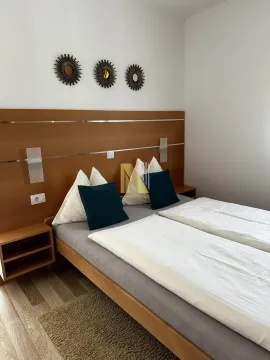 Furnished bedroom with a double bed and wooden headboard. - image 15