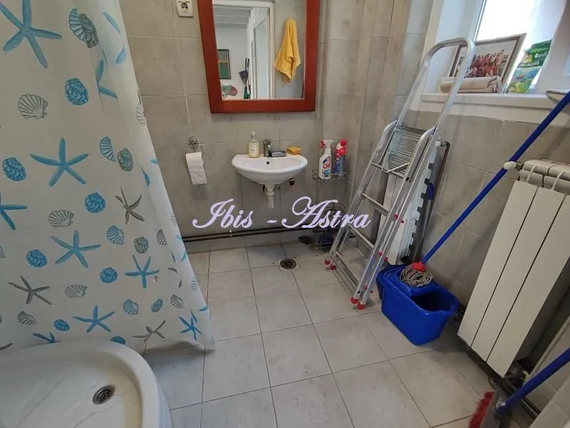 Small bathroom with a shower cabin, sink, and tiled floors and walls.