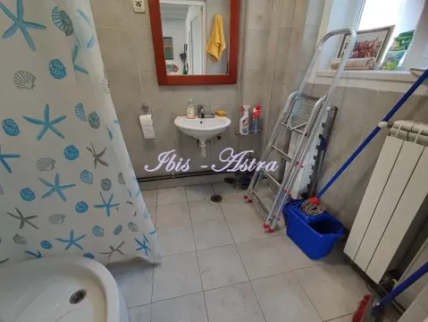Small bathroom with a shower cabin, sink, and tiled floors and walls. - image 9