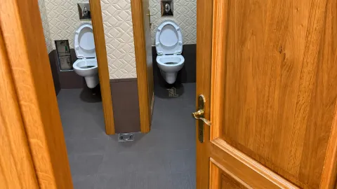 View through an open door into a bathroom with two toilets. - image 6