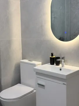 Modern bathroom with a sink, toilet, and illuminated mirror. - image 7