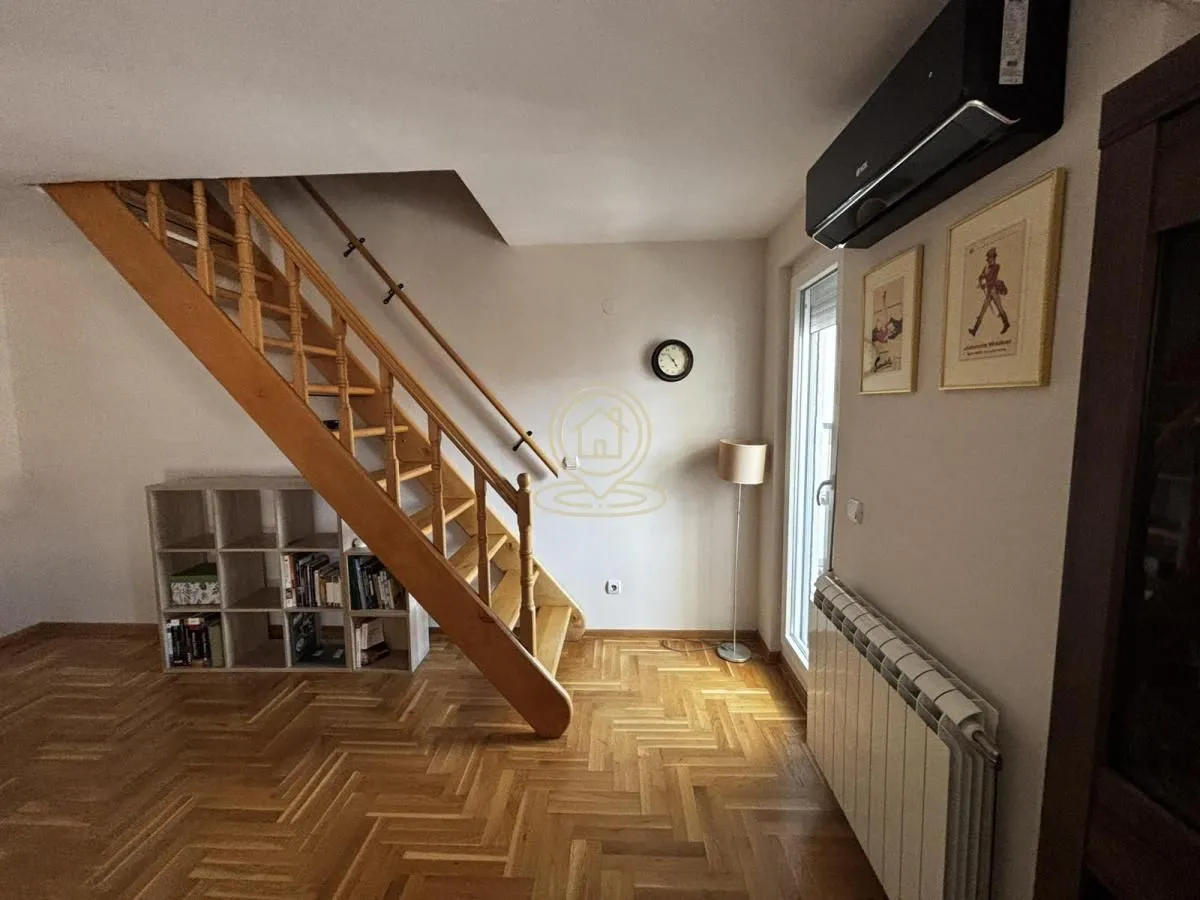 Living room with a wooden staircase and parquet flooring.