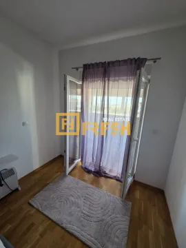 Prazna soba sa drvenim podom, tepihom i balkonskim vratima. - image 3