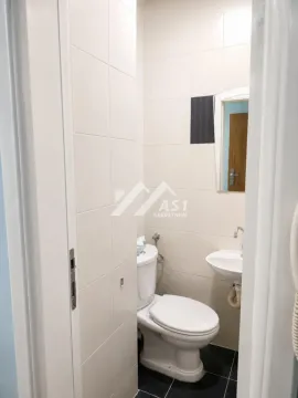 Manje kupatilo sa toaletom i umivaonikom obloženo svetlim pločicama. - image 8