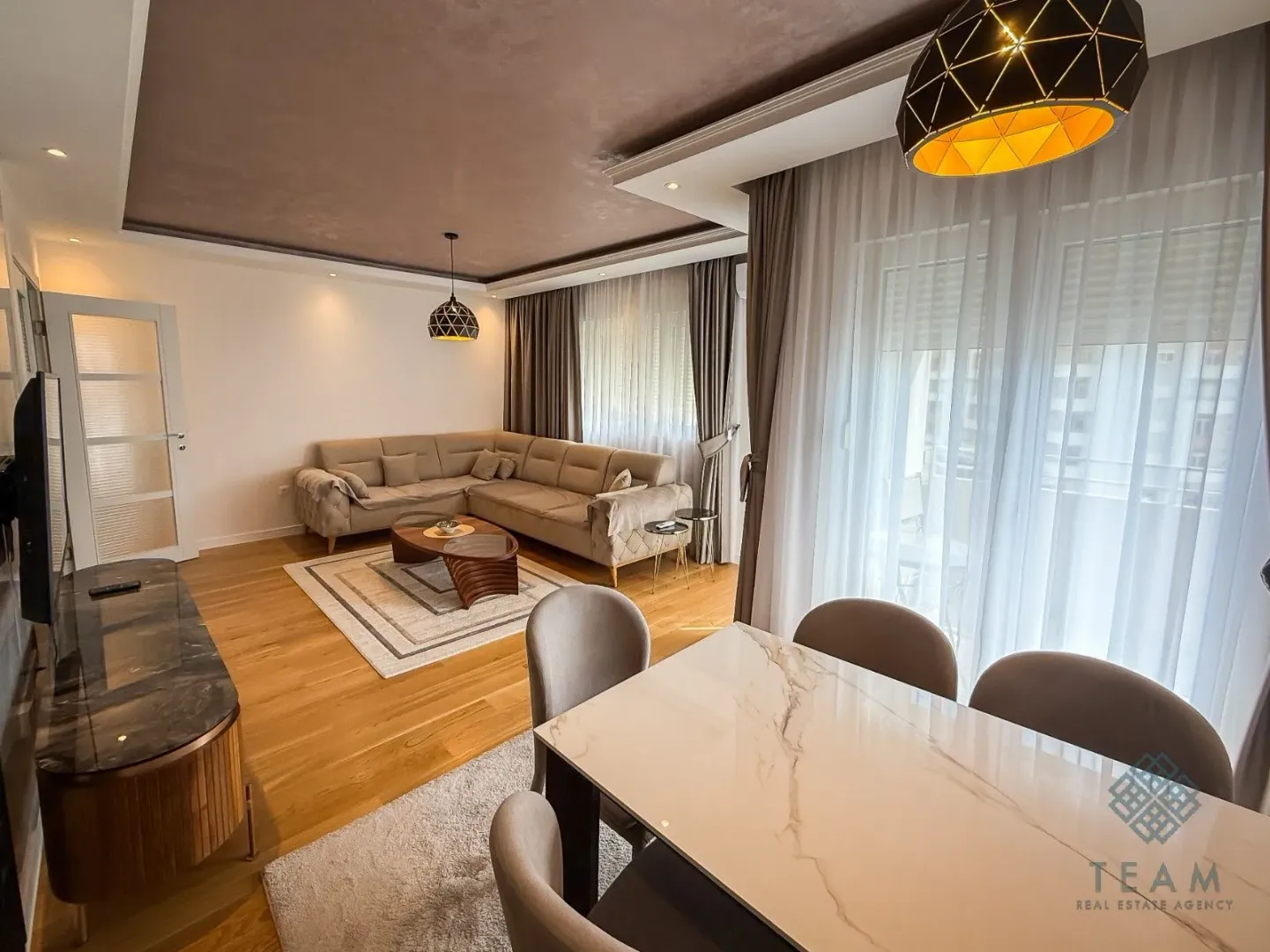 Living room with sofa, dining table and hardwood flooring.