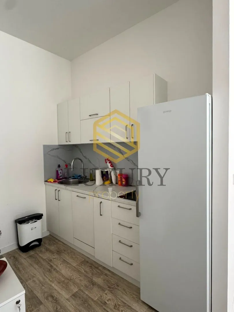 Small white kitchen with a sink and refrigerator.