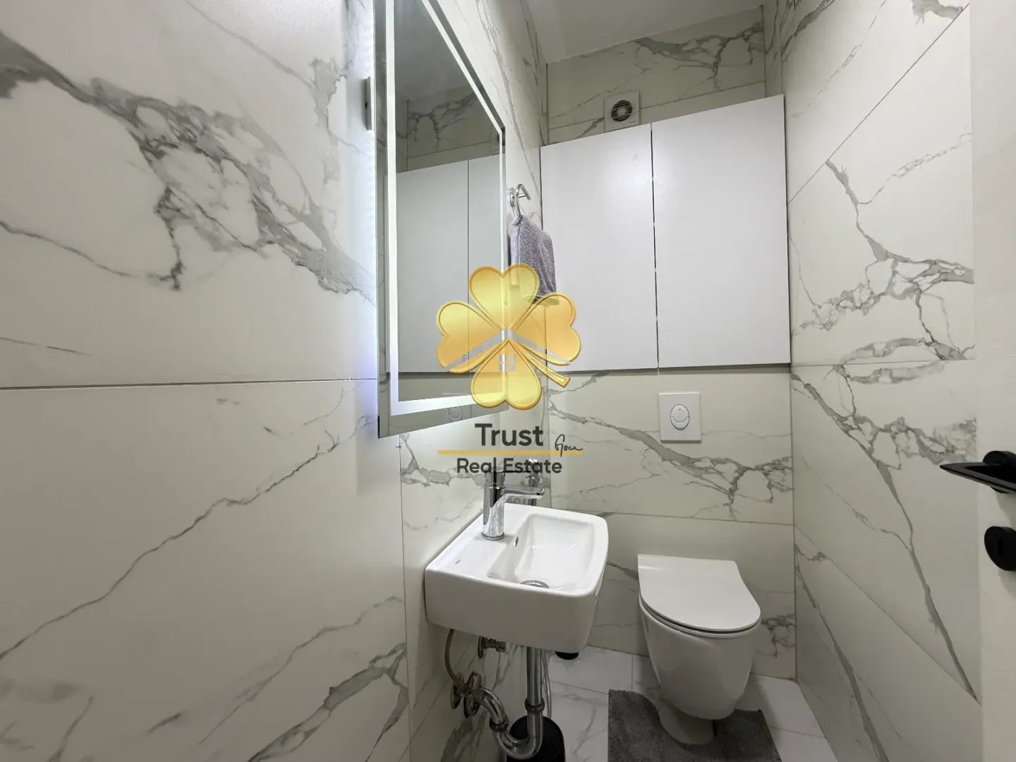 Modernly equipped bathroom with marble tiles, washbasin and toilet.