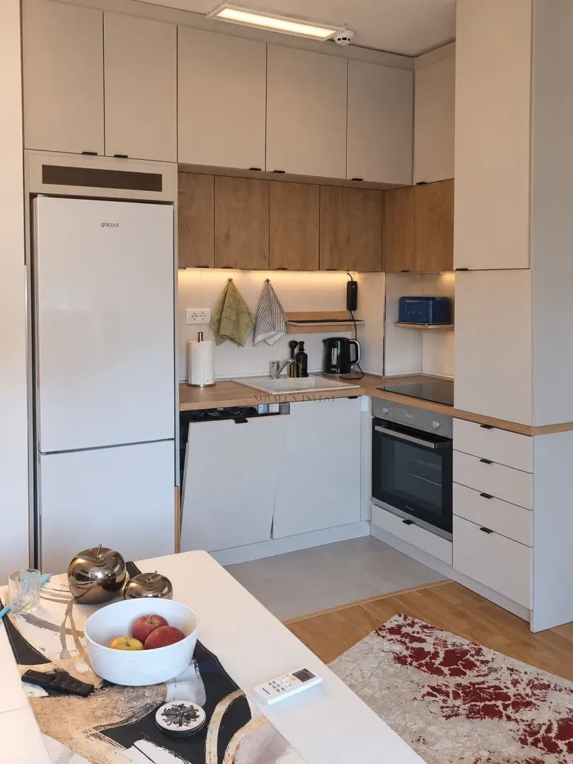 Modern kitchen with built-in appliances and a dining table in the foreground.