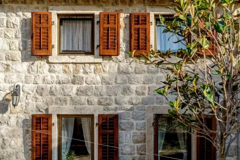 Fasada tradicionalne kamene kuće sa drvenim škurama i prozorima. - image 20