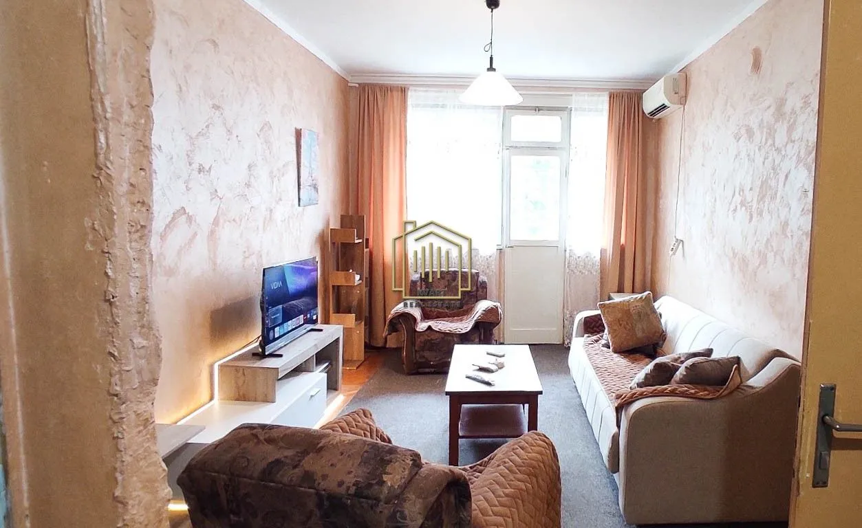 Living room with sofa set, television, and balcony access.