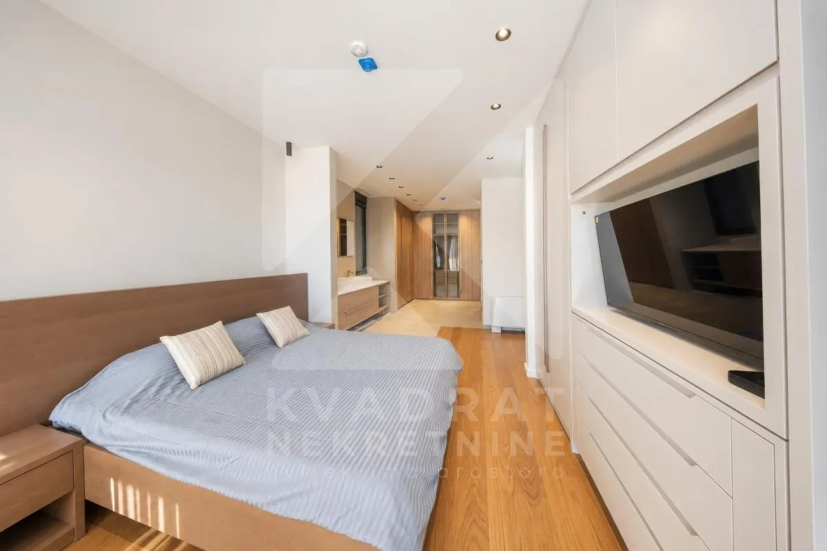 Modern bedroom with a double bed, built-in wardrobes, and a TV.