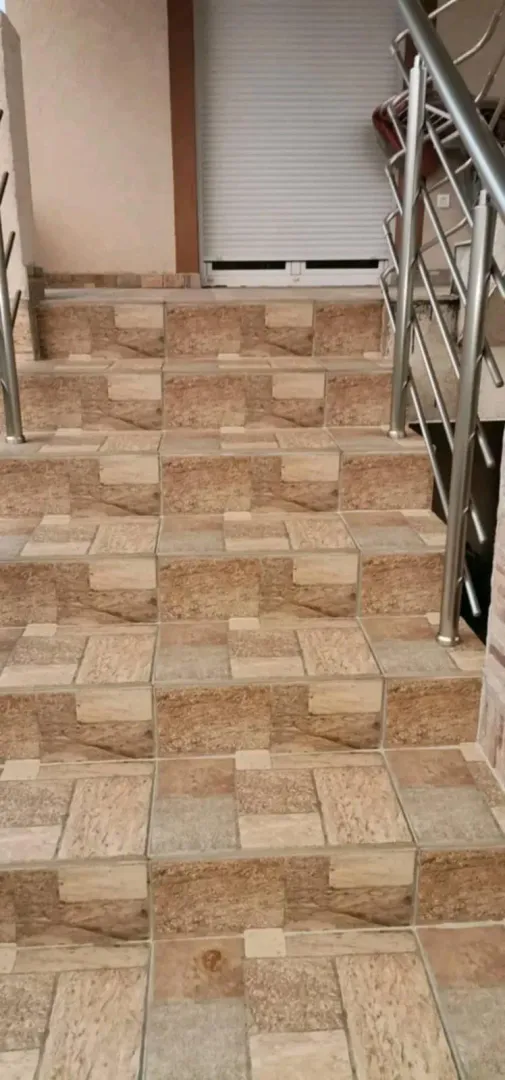 Outdoor tiled stairs with a metal railing.
