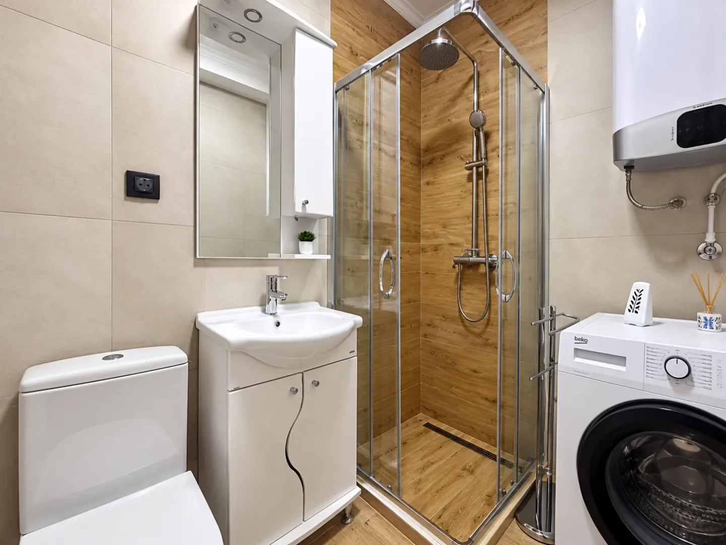 Modernly equipped bathroom with a shower cabin, washbasin, and washing machine.