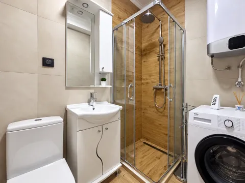 Modernly equipped bathroom with a shower cabin, washbasin, and washing machine. - image 10