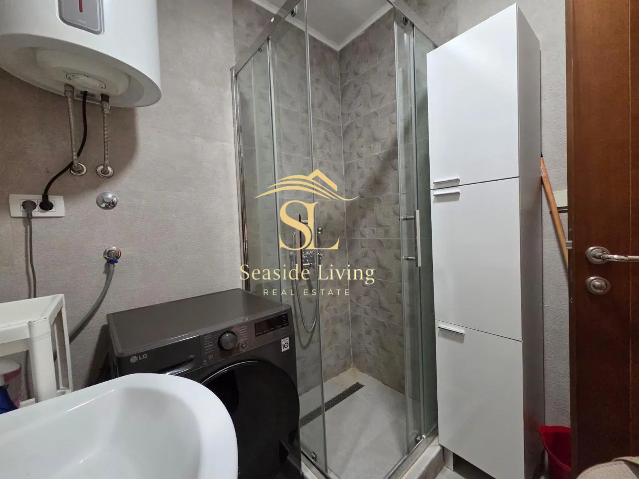 Bathroom with a shower cabin, washbasin, and washing machine.