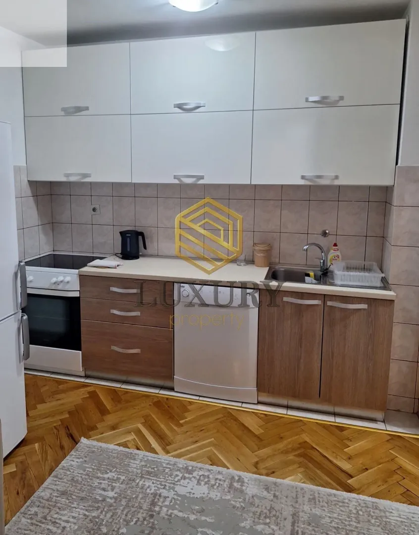Smaller kitchen with white upper cabinets and wooden lower cabinets.