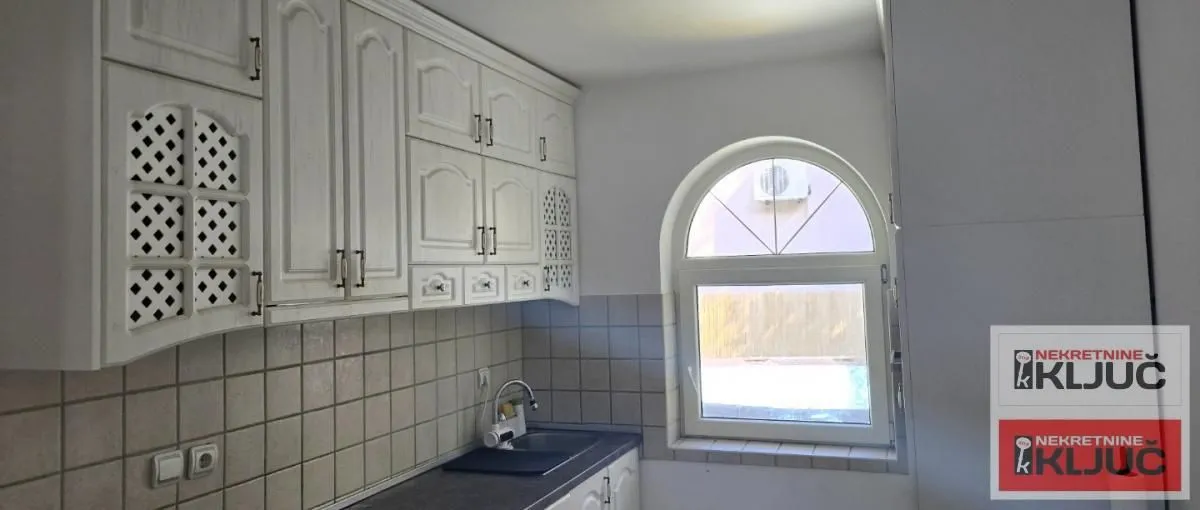 Small kitchen with white cabinets and a window on the wall.