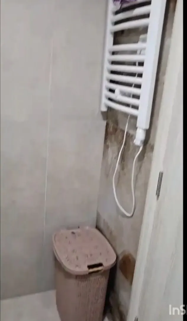 Dio kupatila sa zidnim grijačem i korpom za veš.