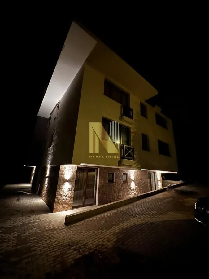 Noćni izgled moderne kuće sa osvetljenjem i dvorištem.