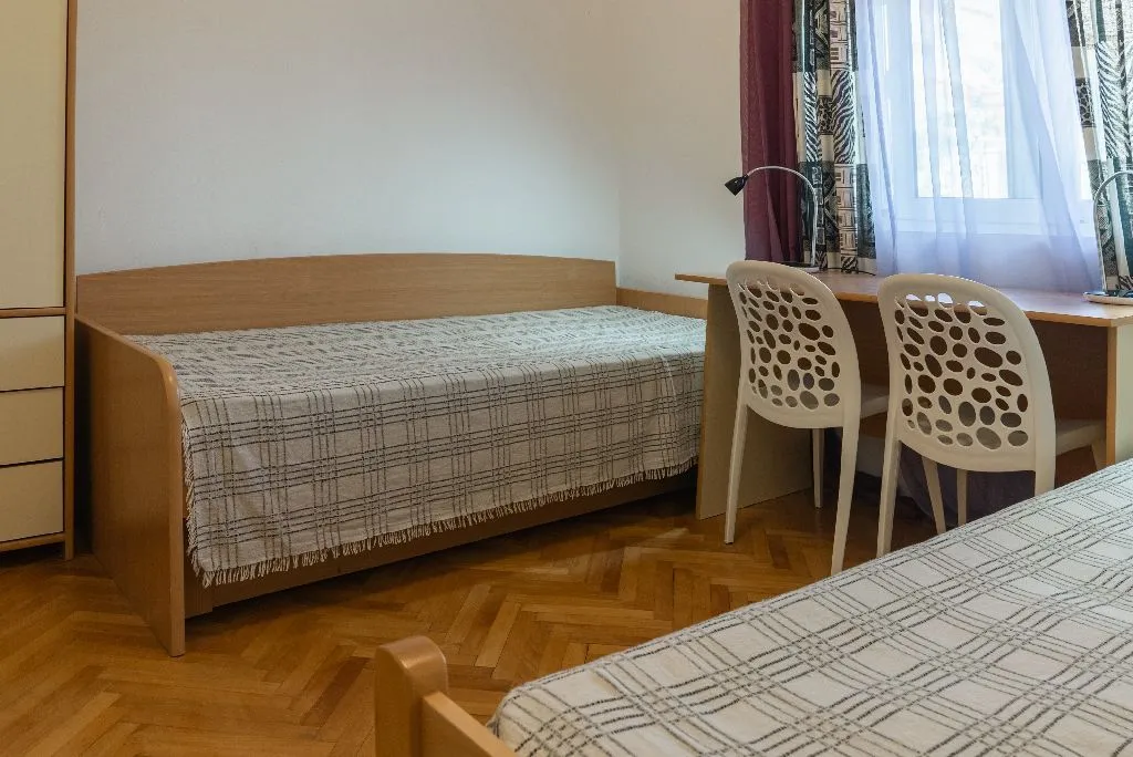Spavaća soba sa dva kreveta i radnim stolom pored prozora.