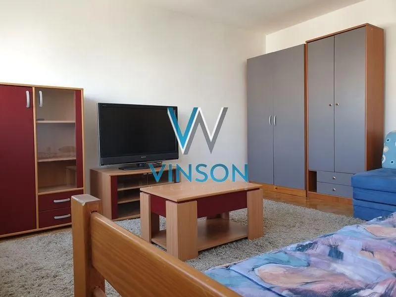 Nameštena spavaća soba sa krevetom, televizorom, ormarima i tepihom.