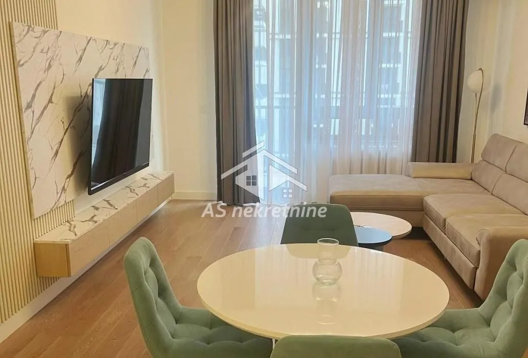 Living room with a sofa, TV, and a dining table with chairs.