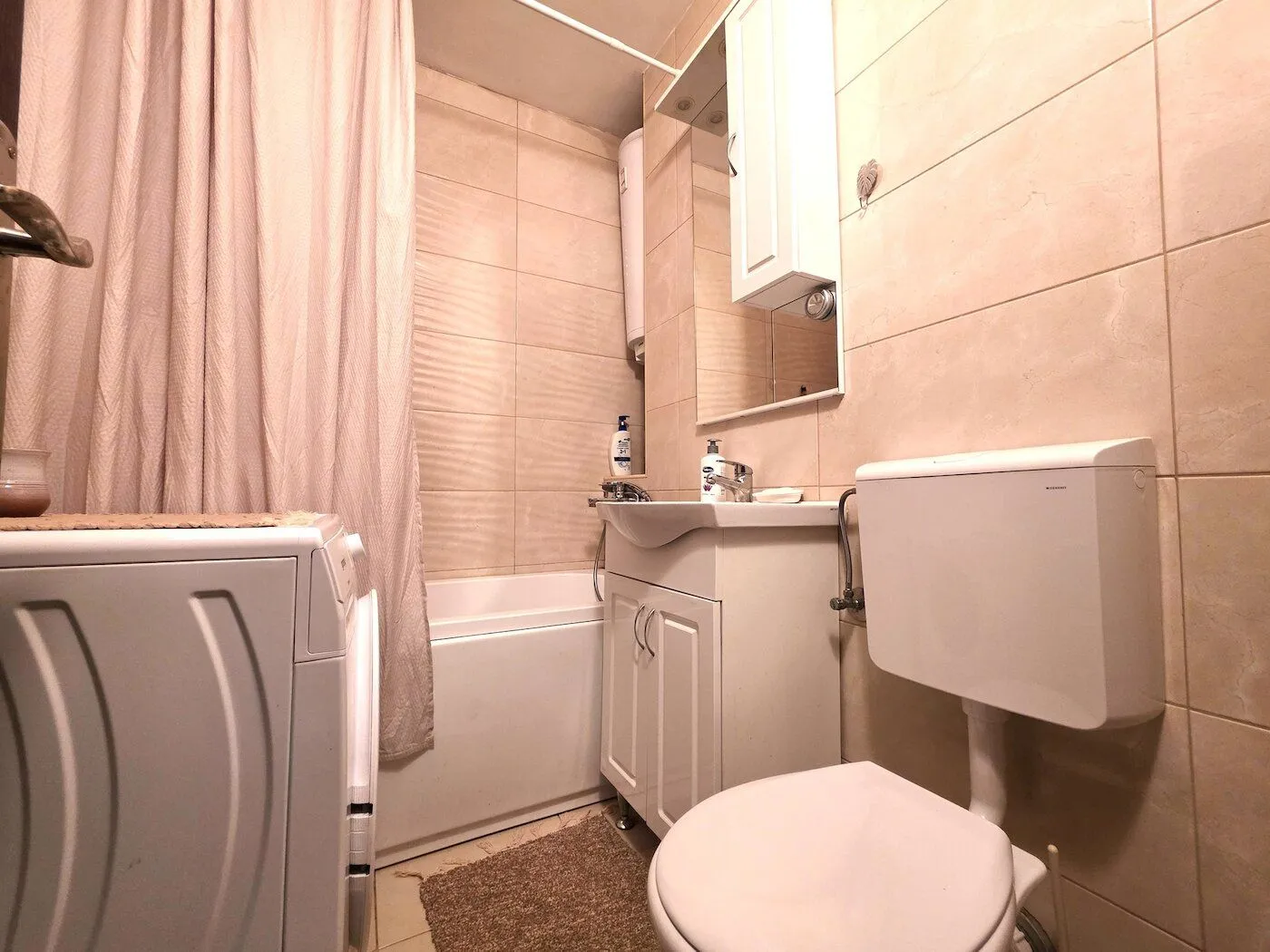 A compact bathroom equipped with sanitary fixtures, a bathtub, and a washing machine.