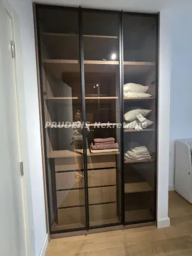 Ugradni garderober sa staklenim vratima i policama u sobi. - image 13