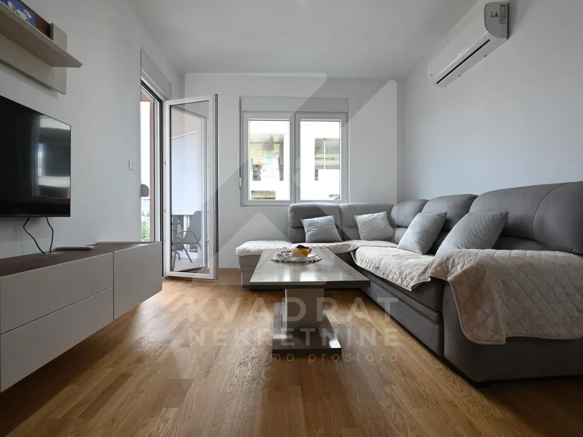 Living room with a corner sofa, coffee table, and wall-mounted TV.