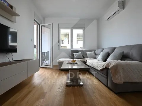 Living room with a corner sofa, coffee table, and wall-mounted TV. - image 16
