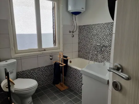 Smaller bathroom with a bathtub, washbasin, toilet, and water heater. - image 2