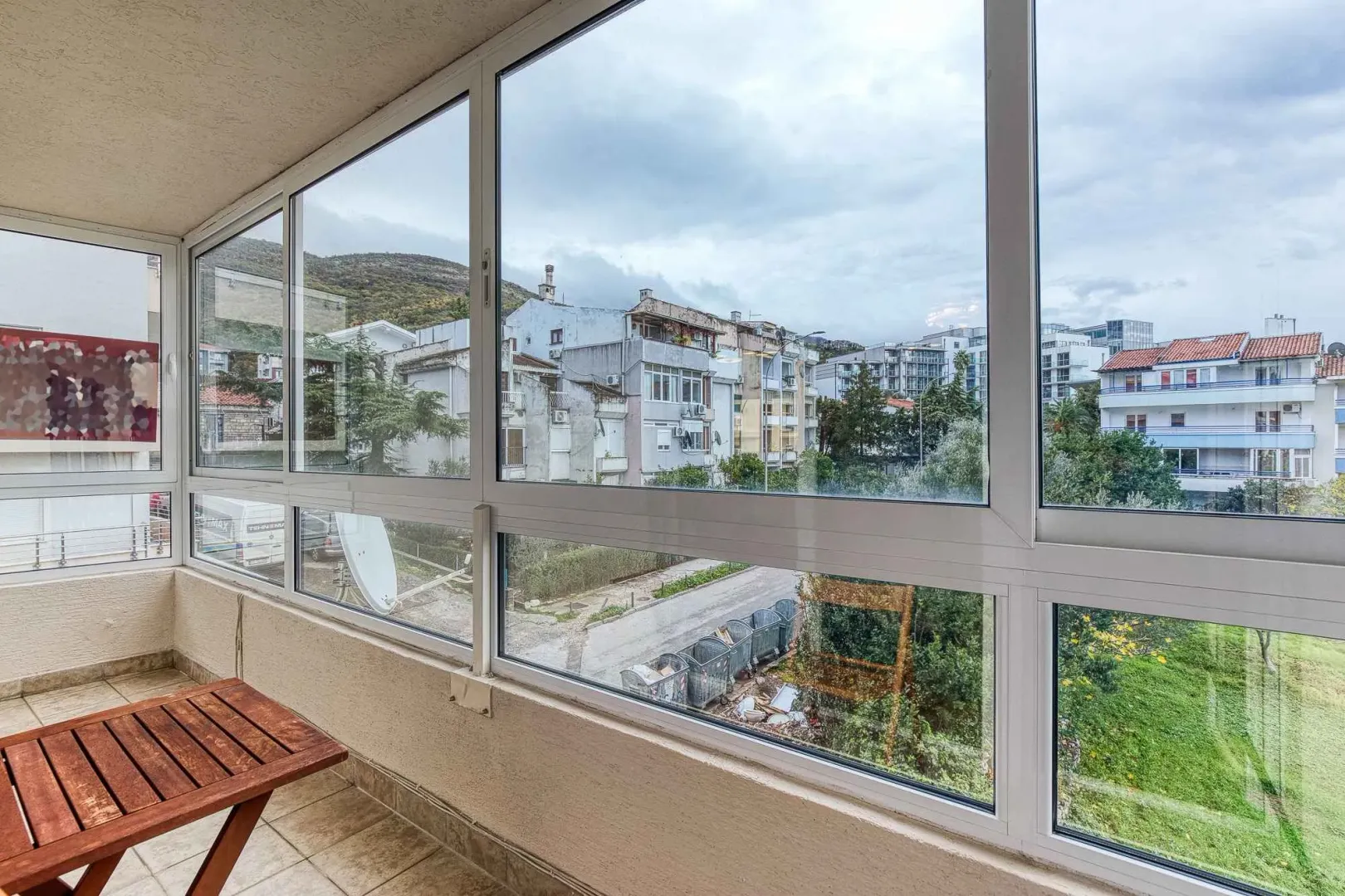 Enclosed balcony with a view of surrounding buildings and the urban neighborhood.