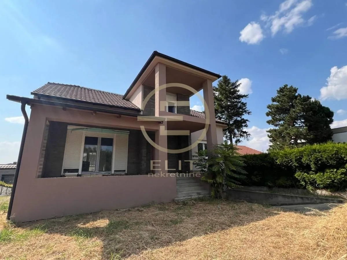 Prednji pogled na spratnu kuću sa terasom i dvorištem.
