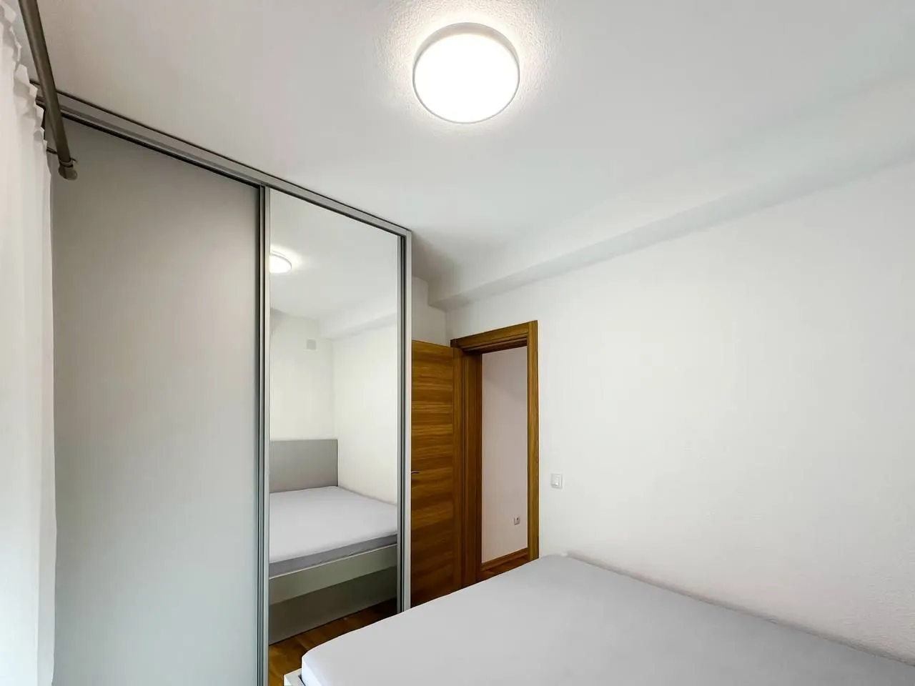 Bedroom with a bed and a large built-in wardrobe with a mirror.