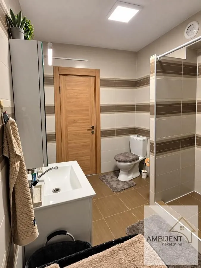 Modernly equipped bathroom with a washbasin, toilet, and walk-in shower.