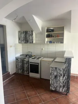 Small kitchen with a stove, refrigerator, and wood-patterned cabinets. - image 7