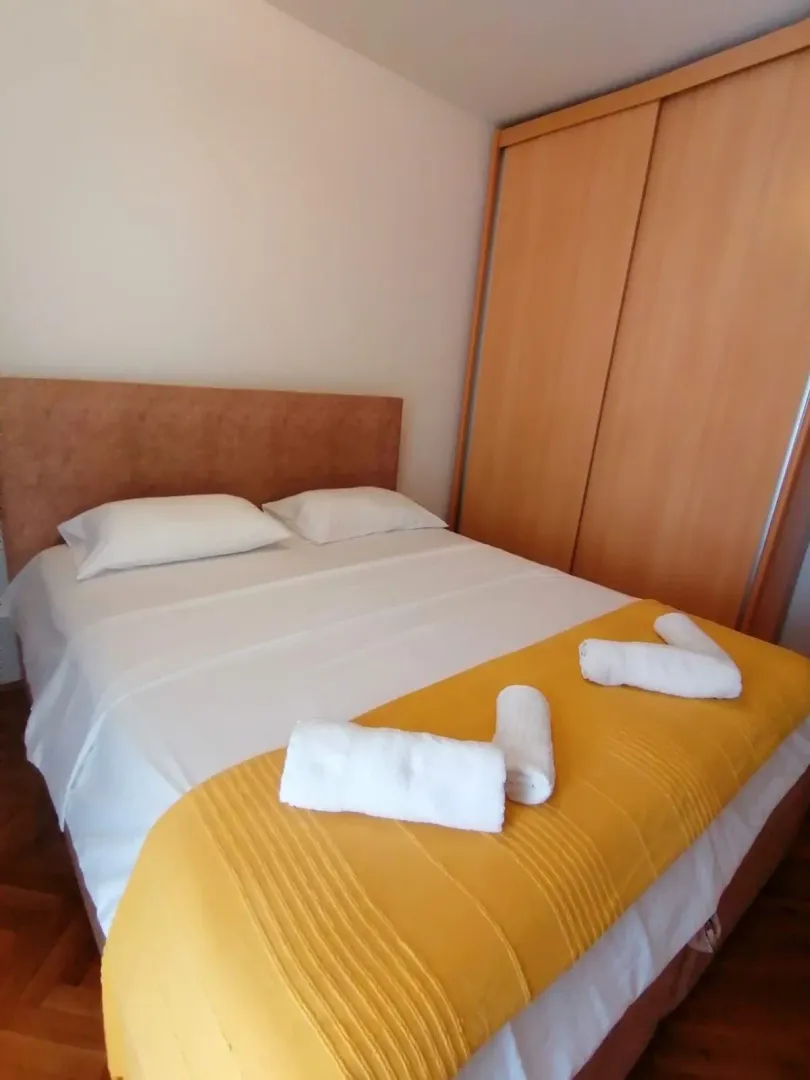 Uređena spavaća soba sa bračnim krevetom i ugradnim plakarom.