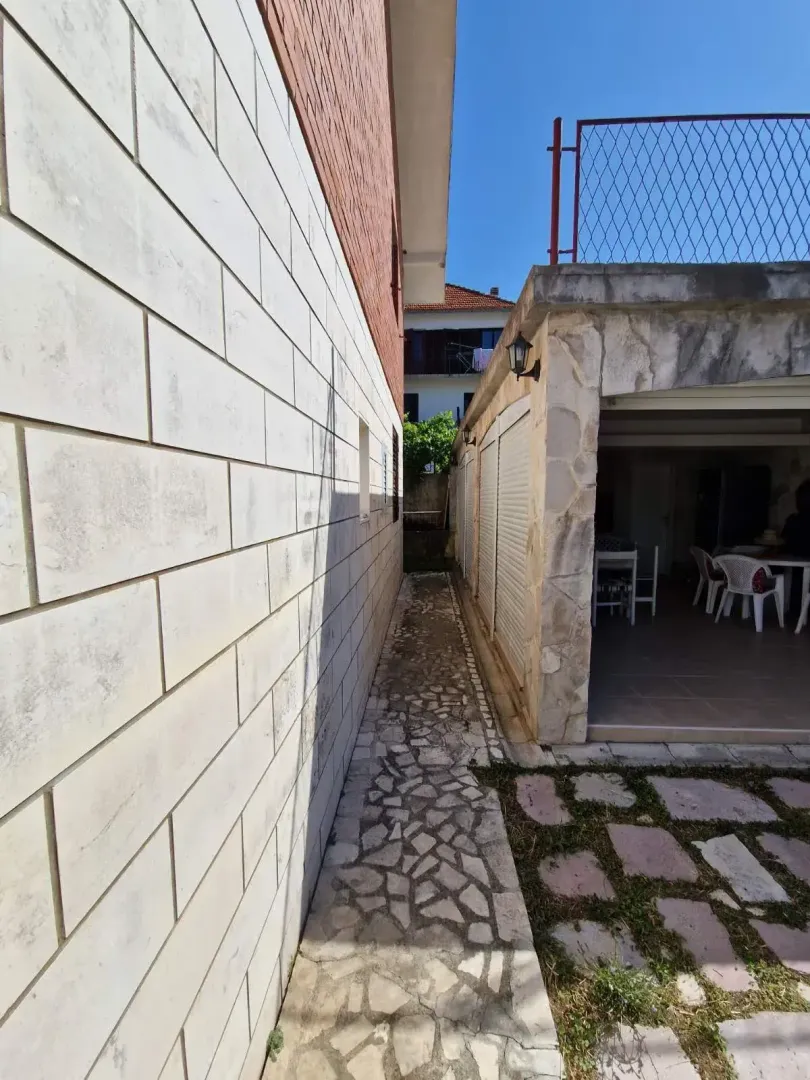 Prolaz između zgrada sa popločanim stazama i natkrivenim dijelom u prizemlju.