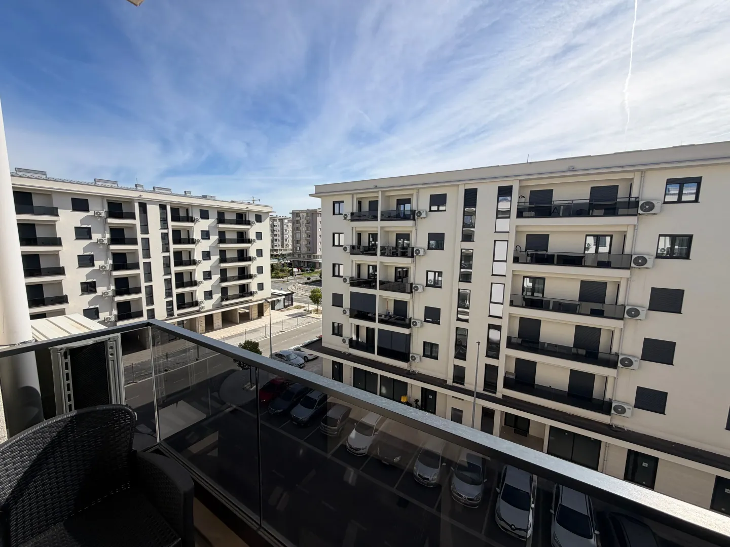 View from the balcony overlooking surrounding residential buildings and parking.