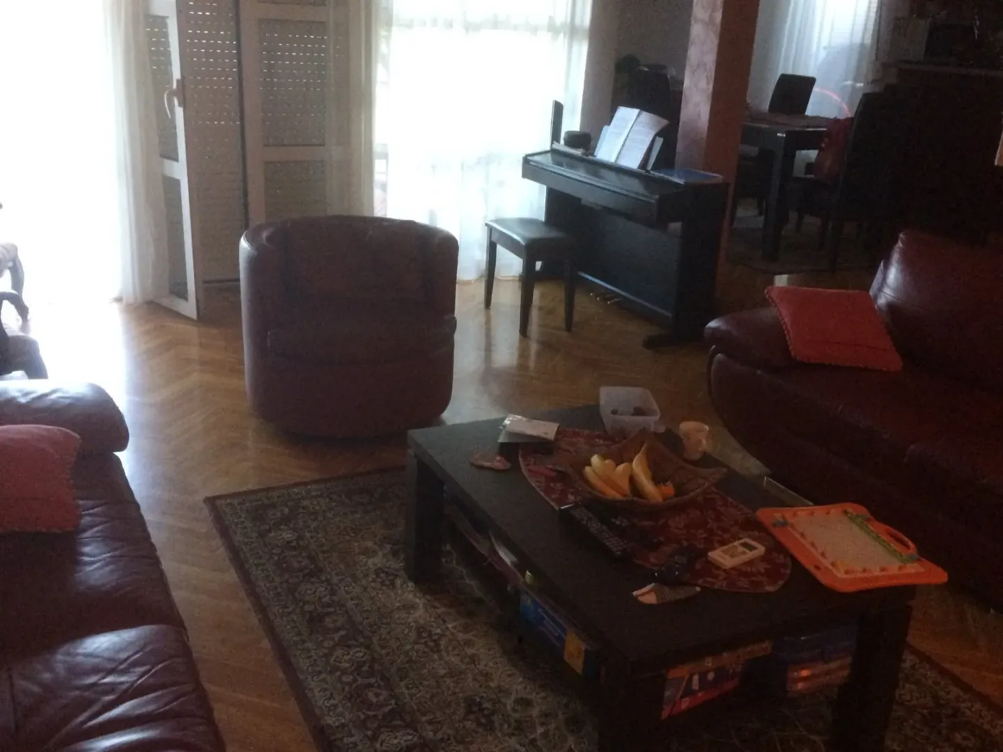 Dnevna soba sa kožnim namještajem, klub stolom i pianinom u pozadini.