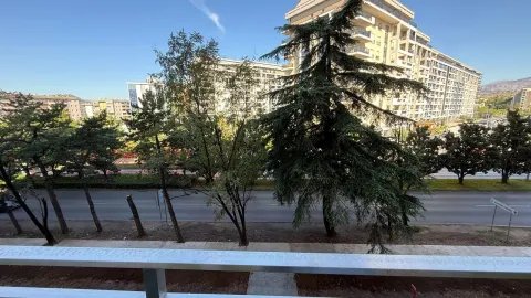 View from the terrace overlooking the street, greenery, and surrounding buildings. - image 4